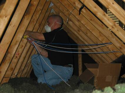Doug works in the attic to get the cabling down the walls to the second floor